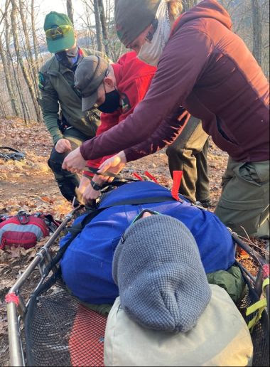 Forest Rangers splinting a hiker's leg in the woods