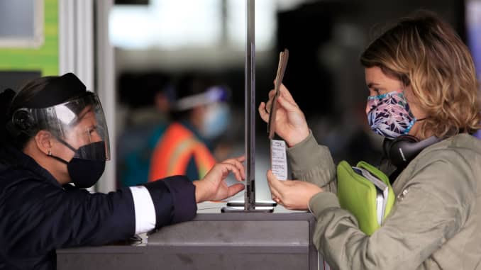 Uma passageira usando uma máscara facial mostra seu passaporte e cartão de embarque para um funcionário em um posto de controle de segurança no Aeroporto Internacional El Dorado, em Bogotá, em 1º de setembro de 2020.