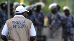 Un journaliste se tient devant les forces de sécurité venues empêcher une manifestation devant le Palais des Congrès de Lomé, le 19 février 2013. (Photo: Daniel Hayduk / AFP)