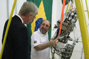 Dr Francis Collins observes as researchers demonstrates movement of a large metal robot, Brazilian flag in background