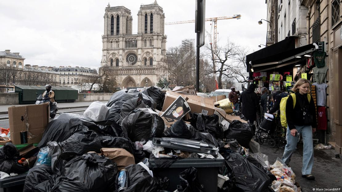 Sacos de lixo amontoados em rua de Paris, com a Notre Dame ao fundo