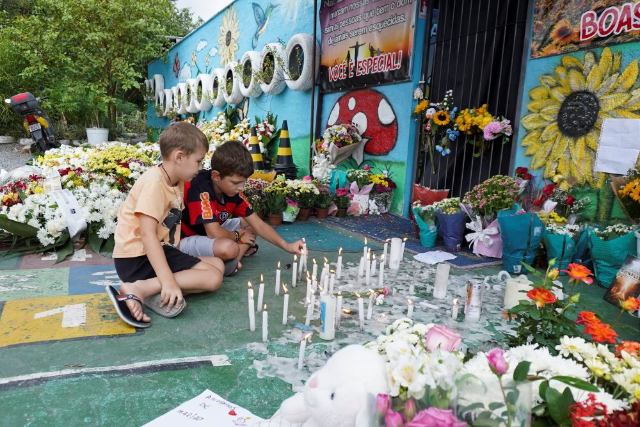 Children light candles during a tribute to victims of a fatal attack at the Cantinho do Bom Pastor daycare center, in Blumenau, in the southern Brazilian state of Santa Catarina, Brazil, April 6, 2023