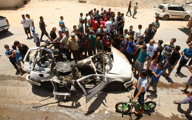 Palestinians gather around the remains of a car which police said was targeted in an Israeli airstrike in the northern Gaza Strip.
