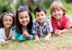 Photo of four smiling children on the grass