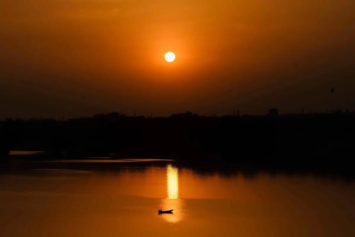 प्रयागराज में सूर्यास्त के समय नदी पार करती हुई नाव