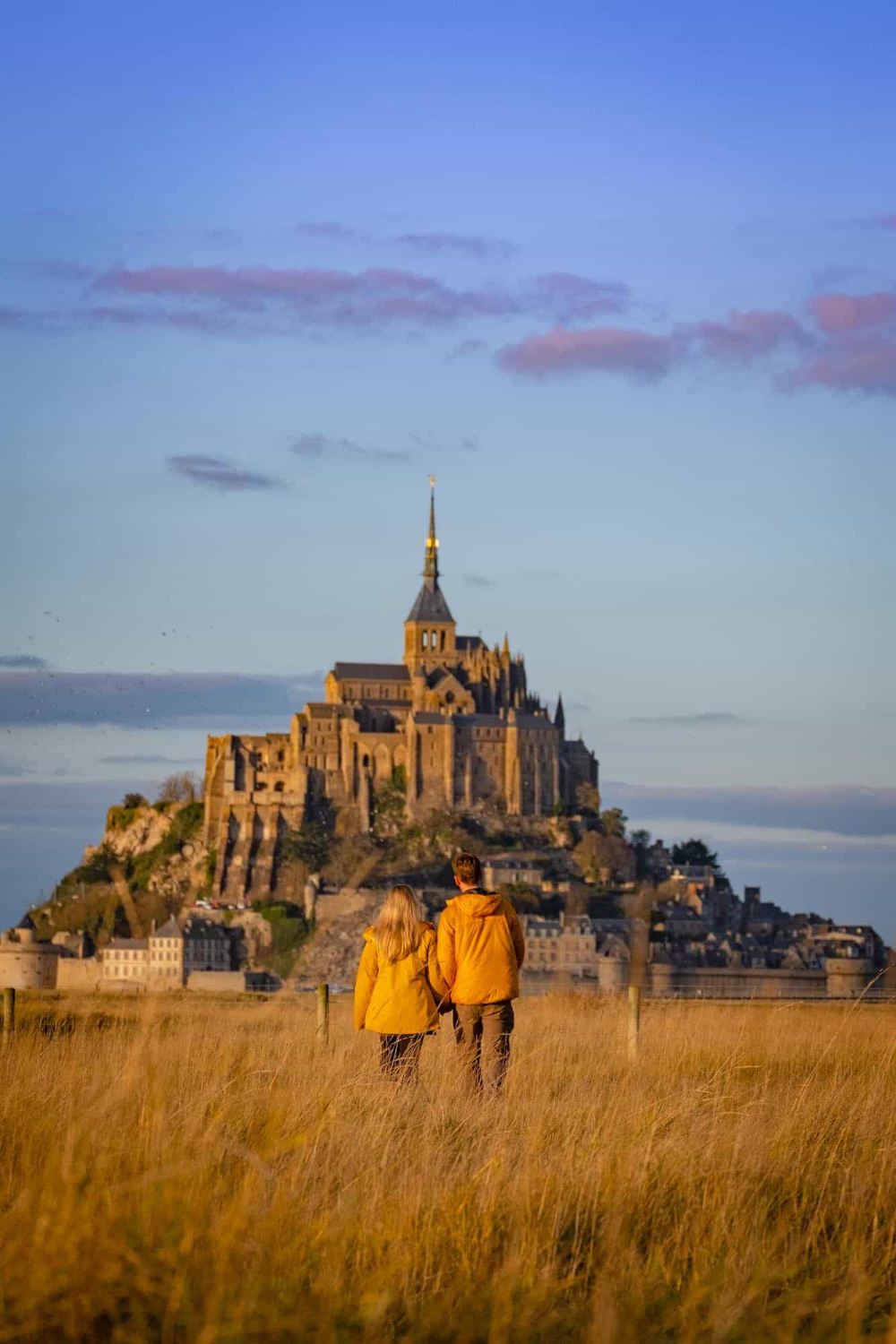 Also known as the parisian riviera. two people standing in front of an old castle on top of a hill with