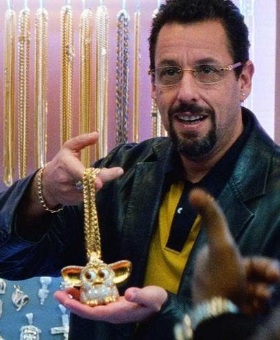 Adam Sandler holds up a diamond Furby on a chain
