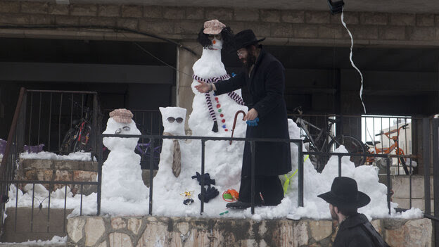 An Ultra Orthodox Jewish man builds a snowman on Friday in Jerusalem. An Ultra Orthodox Jewish man builds a snowman on Friday in Jerusalem.