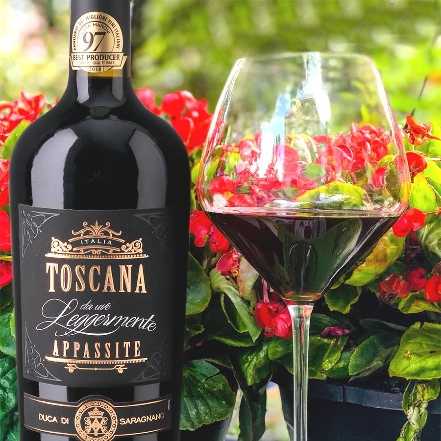 Bottle and glass of Toscana Rosso da Uve Leggermente Appassite set among vibrant red blossoms.