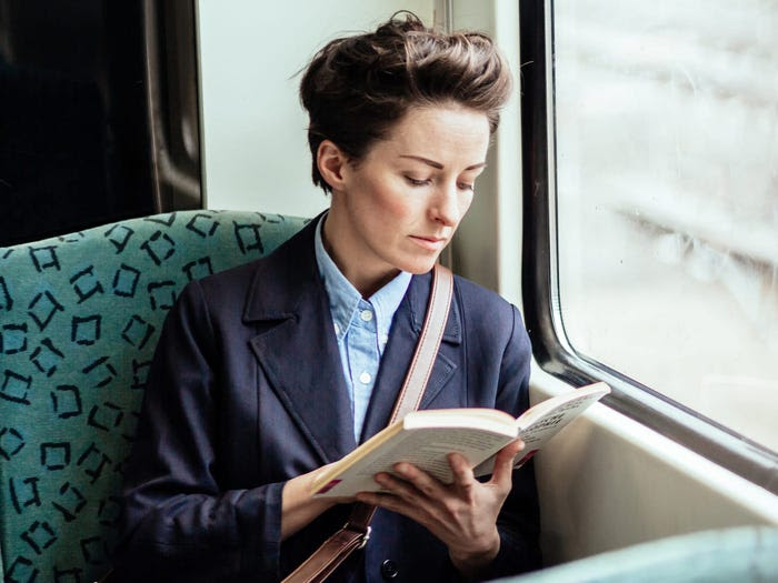 woman reading a book on the train