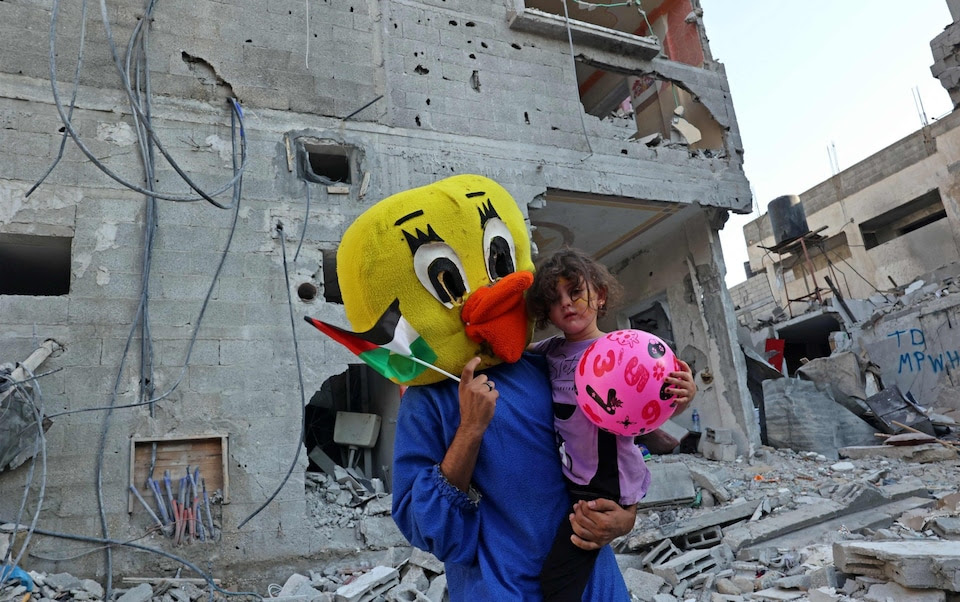 A Palestinian clown carries a child during a show amid the rubble of a building destroyed in the latest round of fighting between Israel and Palestinian militants, in Rafah in the southern Gaza Strip.