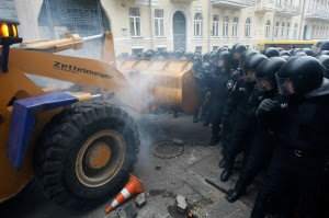People use a tractor while trying to break through police lines near the presidential administration building during a rally held by supporters of EU integration in Kiev