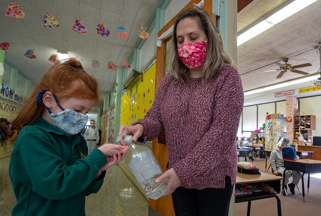 Kindergarten teacher Heather Brandt, of Levittown, squirts hand sanitizer on the hands of Nadia Lentz, 6, of Levittown, before she reenters the classroom at St. Michael the Archangel.