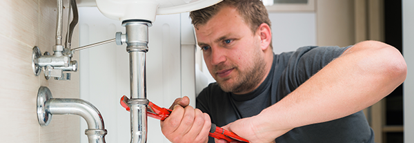 Plumber fixing pipes underneath sink