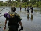 A Border Patrol agent watches as a group of migrants walk across the Rio Grande on their way to turn themselves in upon crossing the U.S.-Mexico border, Tuesday, June 15, 2021, in Del Rio, Texas. U.S. government data shows that 42% of all families encountered along the border in May hailed from places other than Mexico, El Salvador, Guatemala and Honduras the traditional drivers of migratory trends. (AP Photo/Eric Gay)