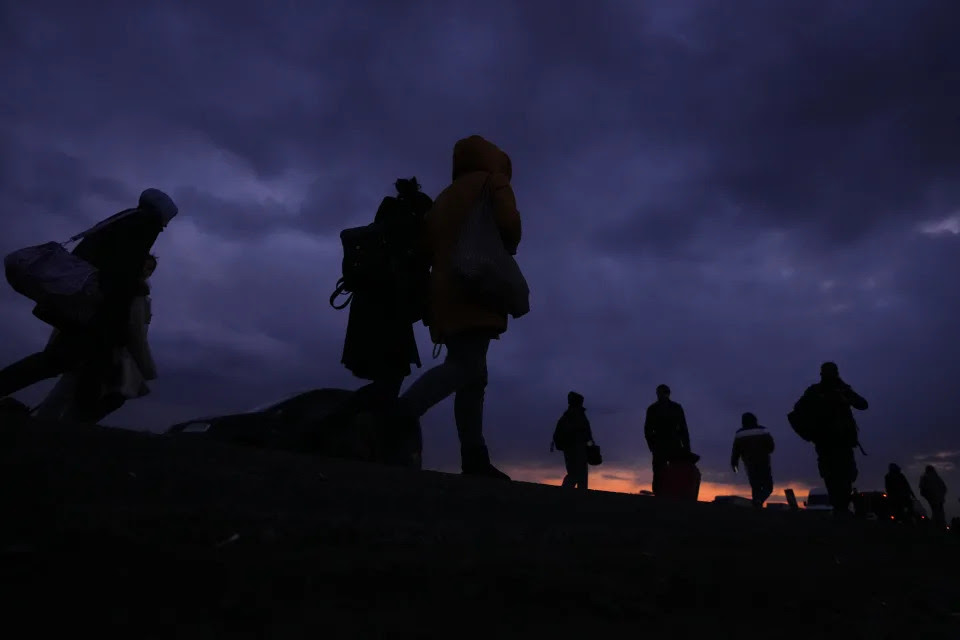 Refugees arrive in Przemysl, Poland, against a dark sky as night closes in.