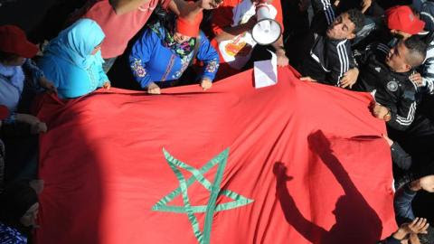 Moroccan protesters hold giant national flag during a protest outside the French embassy in Rabat, February 25, 2014, following diplomatic tensions raised by civil lawsuits filed in Paris accusing Morocco intelligence chief of &quot;complicity in torture&quot;