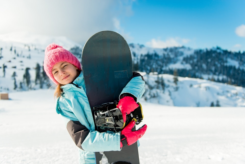 Girl with a snowboard in a ski resort