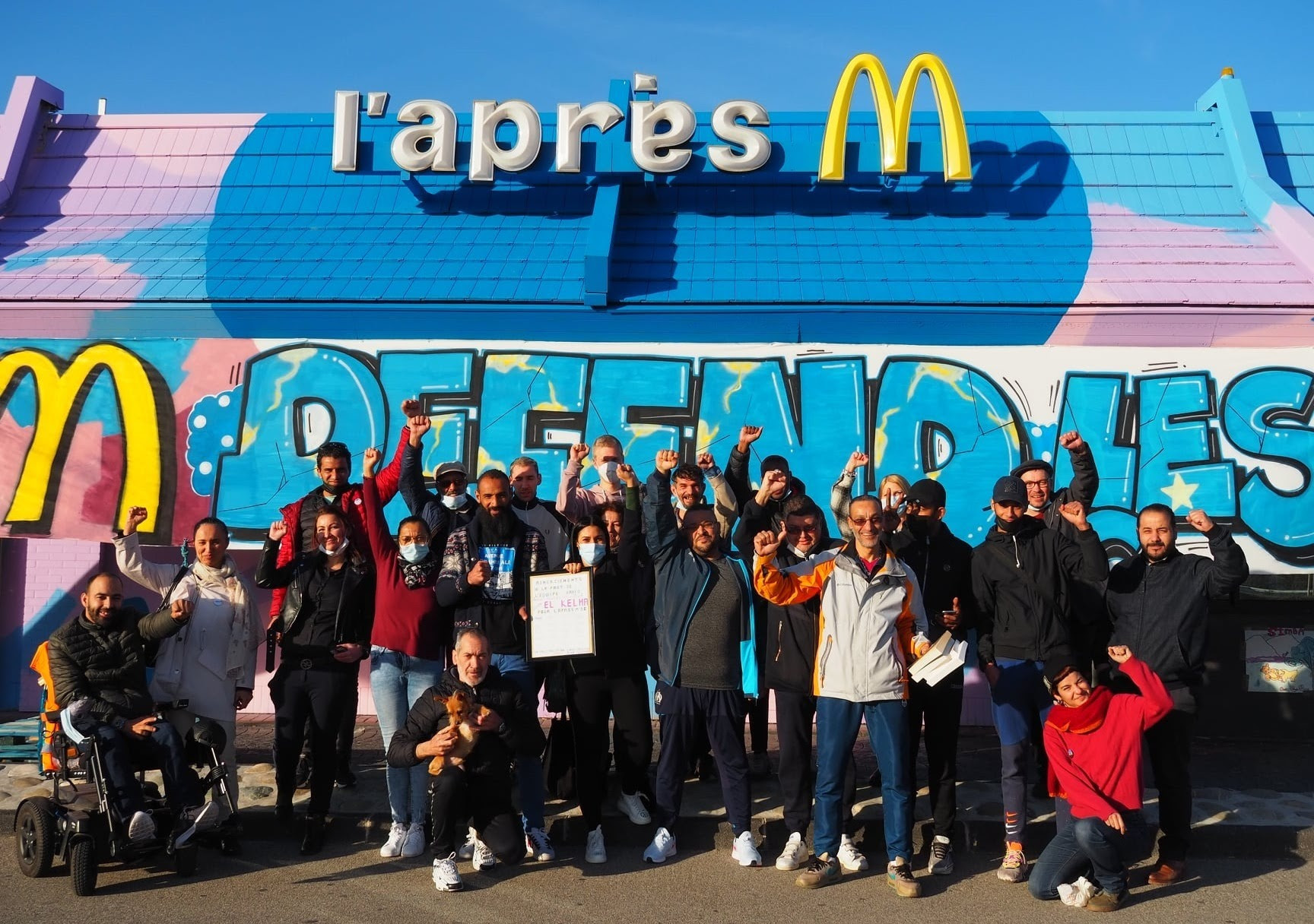 Volunteers and staff of the Après M posing in front of the reconverted McDonald's building