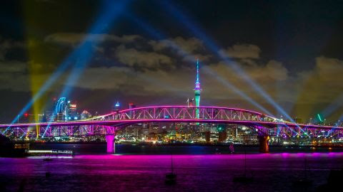 Një shfaqje me dritë nga Skytower dhe ura e portit gjatë festimeve të Vitit të Ri në Auckland, Zelanda e Re, më 1 janar 2022.