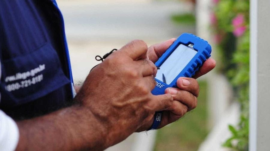 Funcionário do IBGE segura aparelho telefônico onde faz anotações para a realização do Censo 2022