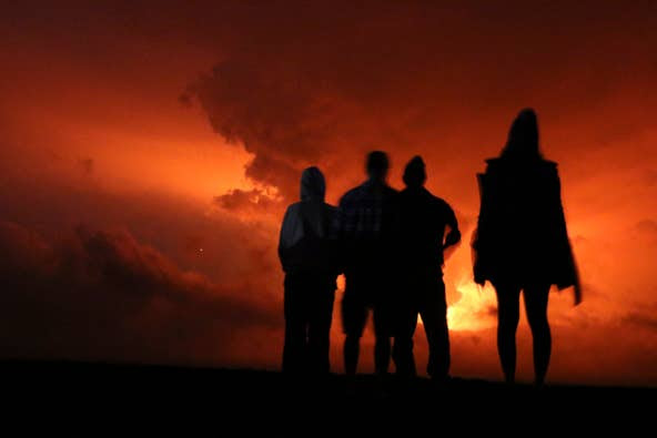 People watch the glow from lava erupting from Hawaii's Mauna Loa volcano, Monday, Nov. 28, 2022 in Hilo, Hawaii.
