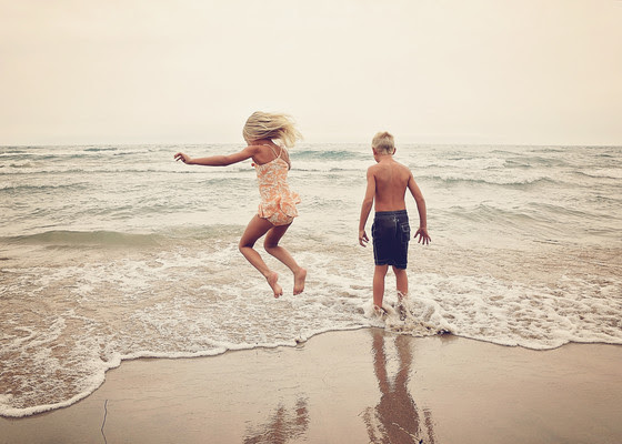 a little boy and a little girl playing on a sandy beach