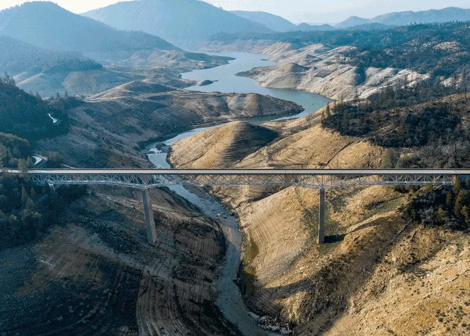 A series of three images framing the same view of a reservoir surrounded by hills, with a bridge running across.