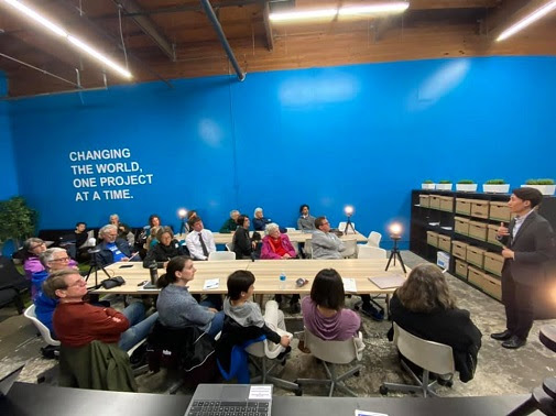 Attendees sit at 2 tables in the Volunteer Center, training to become phonebanking hosts.