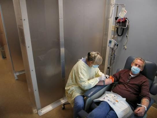 A nurse prepares to treat an adult male patient with a monoclonal antibody through IV.