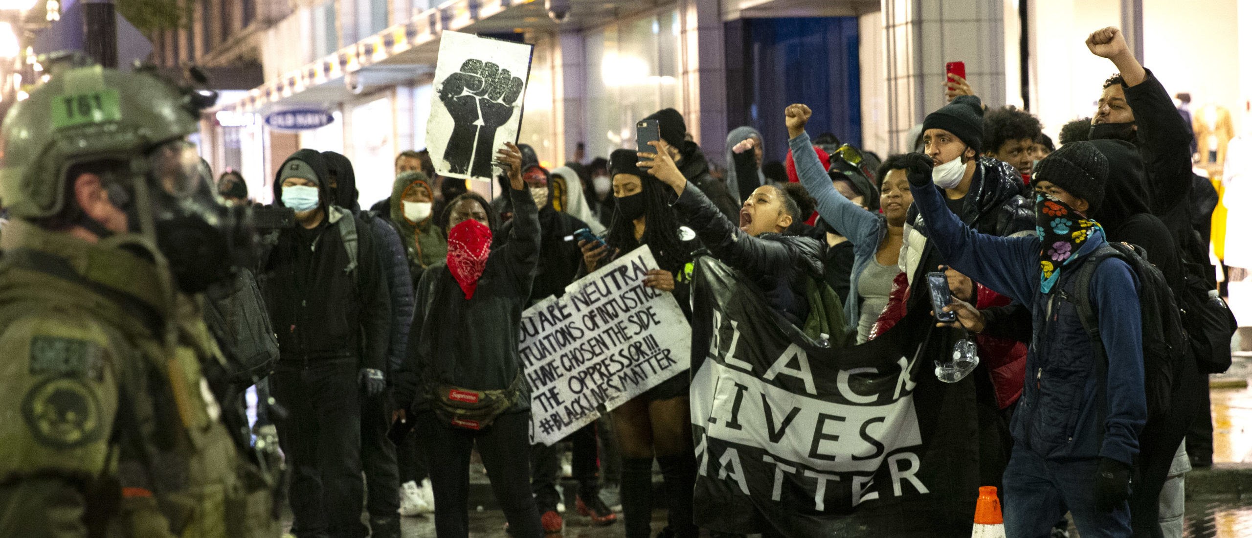 SEATTLE, WA - MAY 30: Protesters holding a Black Lives Matter banner shout at law enforcement officers on May 30, 2020 in Seattle, Washington. A peaceful rally was held earlier in the day expressing outrage over the death of George Floyd who died while in the custody of police in Minneapolis. Police deployed flash bangs and tear gas to break up the crowd who were breaking windows and looting stores. (Photo by Karen Ducey/Getty Images)
