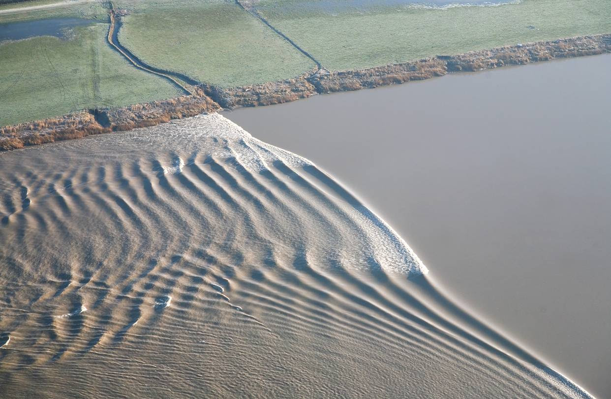 Breaking High tide sweeping up the River Severn in England. The river’s narrow channel funnels the incoming tide into waves big enough for surfing.