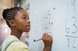 black girl solving math problem on the board