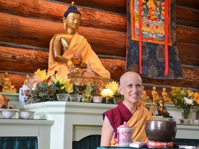 Venerable Thubten Chodron seated before the Buddha while she teaches.