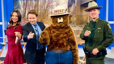 Newscasters, Smokey Bear, and Ranger stand in the studio for a picture