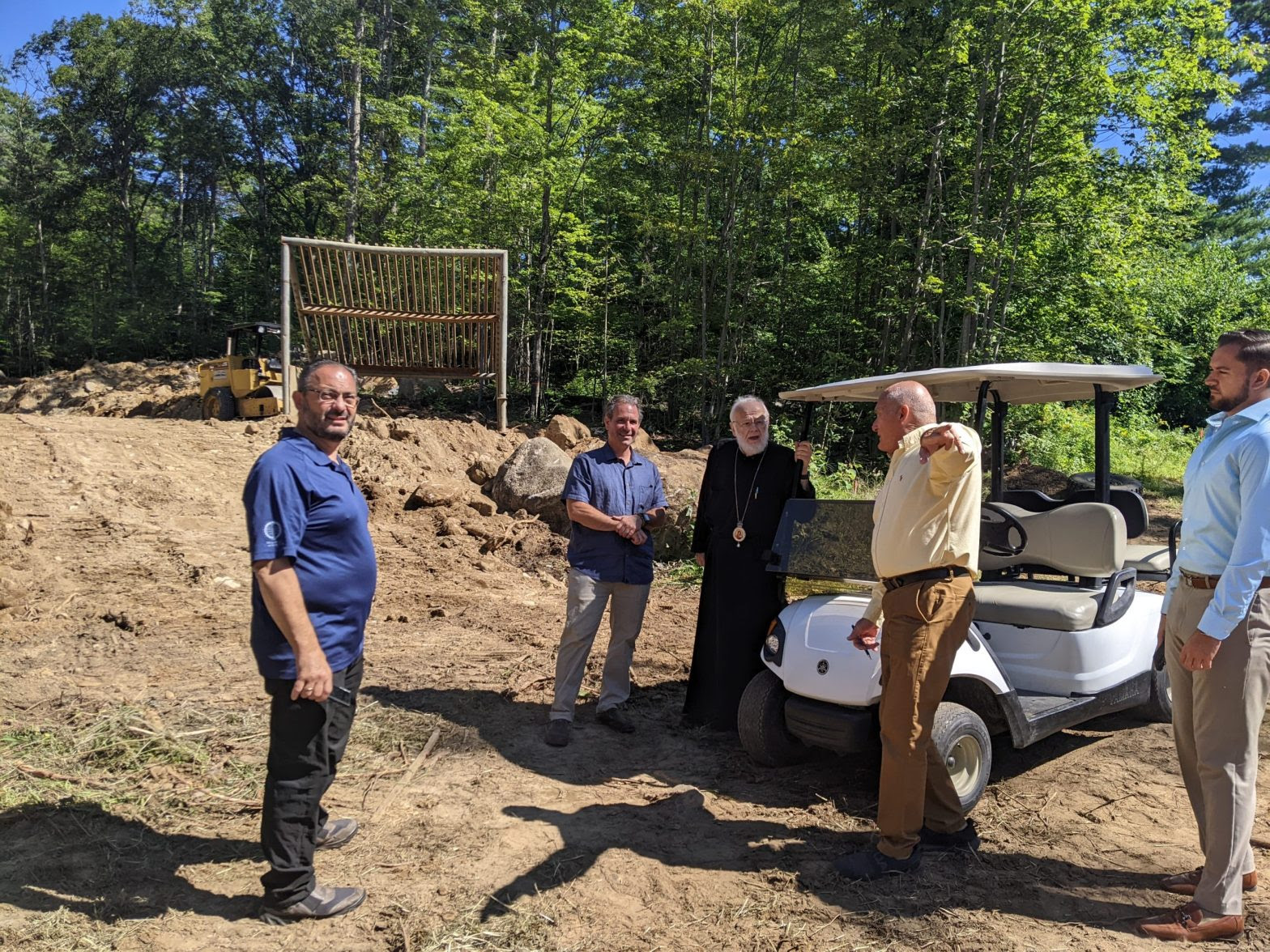 His Eminence Metropolitan Methodios of Boston, is being informed by Gordon Bristol, supervisor of the construction of the gymnasium about the ongoing excavation. Also present are the chancellor Protopresbyter Fr. Theodore Barbas, the director of the Camping Center, Mike Sintros, and the Youth Director, Panagiotis Koufos. (Photo provided by the Metropolis of Boston) ΓΥΜΝΑΣΤΗΡΙΟ-ΚΑΤΑΣΚΗΝΩΣΗ-3-scaled