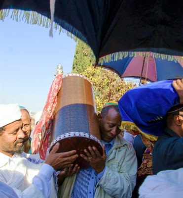 An Ethiopian Jewish
                    man and a Kes, a religious leader of the Ethiopian
                    Jews, carry the Torah.