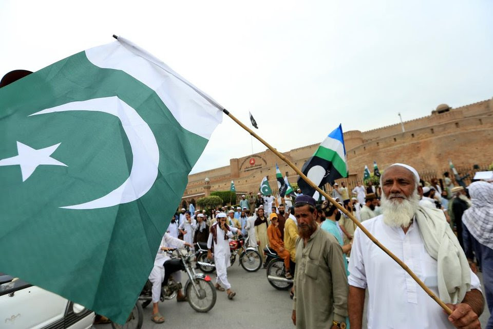 People hold national flags and placards during a protest in front of the paramilitary FC headquarters in Peshawar, Pakistan, on May 10.