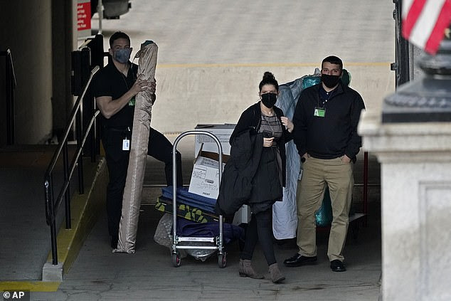 People wait for a moving van as they move boxes out of the Eisenhower Executive Office building on January 14, 2021