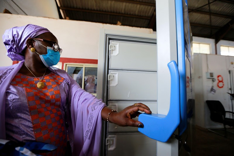 A women in a face mask opens one of the new ultra low temperature freezers at a facility in Nigeria