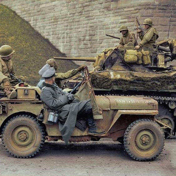 Two high-ranking German Wehrmacht officers being          transported under the watchful eye of soldiers from the 4th          Armored Division in a Ford GPW jeep, pass by a camouflaged M5          Stuart light-tank belonging to the 37th Armored Regiment          during the surrender in Hersfeld, Germany, 31st of March,          1945.