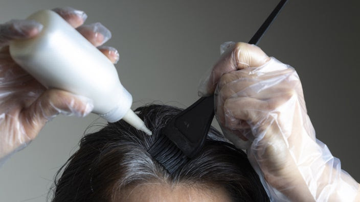 A closeup of someone dying their gray hairs.