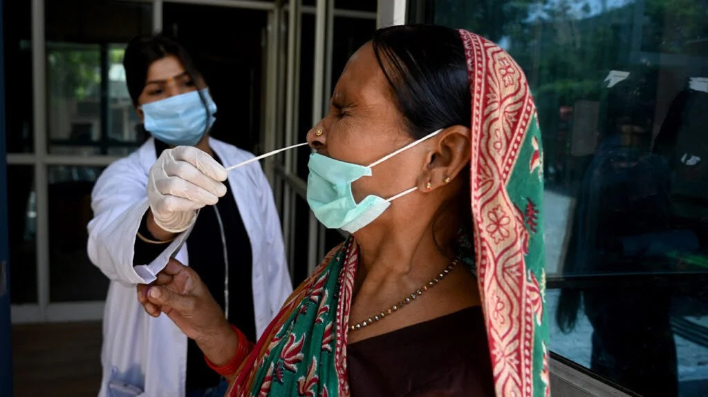 A healthcare professional swabs the nose of a woman wearing a face mask