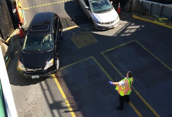 Vessel crewmember directing vehicles onto the car deck of a ferry