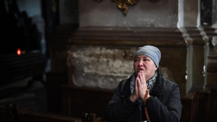 Una donna prega e piange in una chiesa di Lviv, in Ucraina