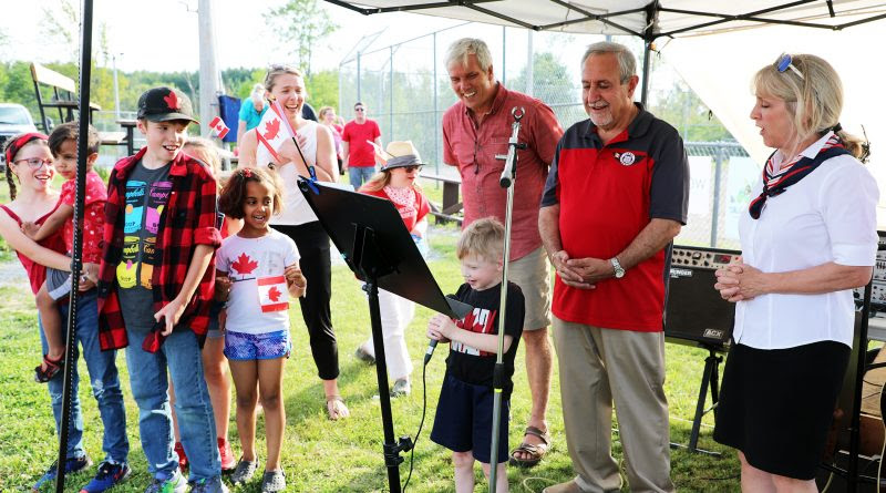 The kids of Dunrobin, led by Weston Braun on the microphone, lead the community in singing O Canada along with DCA President Greg Patacairk, Coun. Eli El-Chantiry, MP Jenna Sudds and MPP Dr. Merrilee Fullerton. Photo by Jake Davies