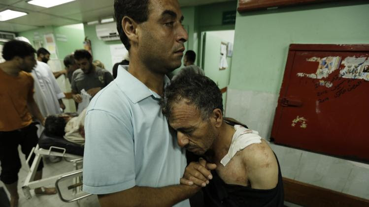 A Palestinian hugs his father who was wounded in an Israeli strike on a compound housing a UN school in Jabaliya refugee camp in the northern Gaza Strip, following their arrival at the Kamal Edwan hospital in Beit Lahia on July 30, 2014