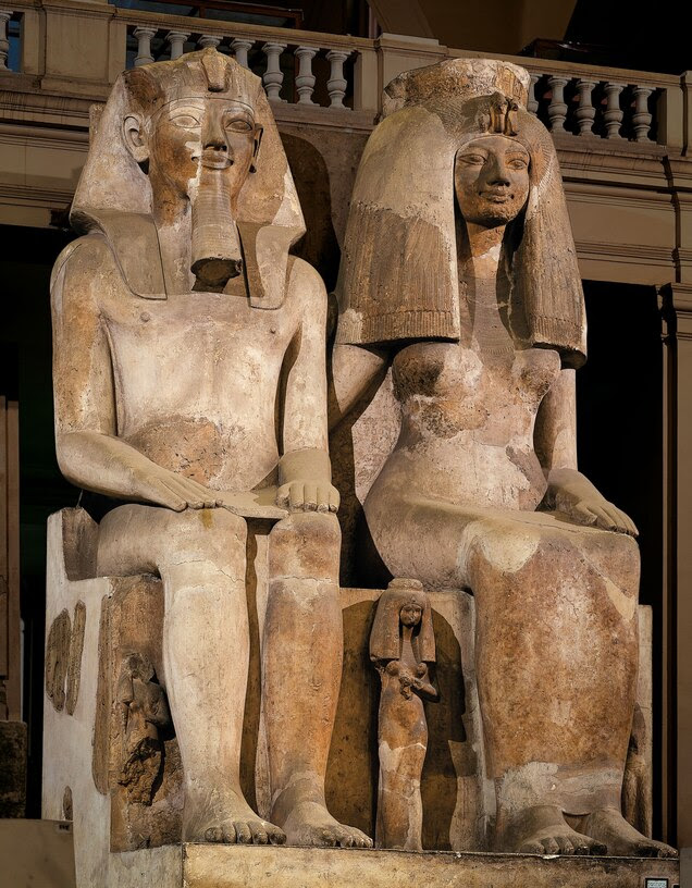 Two large statues of seated figures with a small statue of a standing person between them