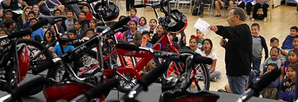 Numerous Central School third grade students smile and scream with excitement when told that they will all be receiving free bicycles thanks to a generous donor.