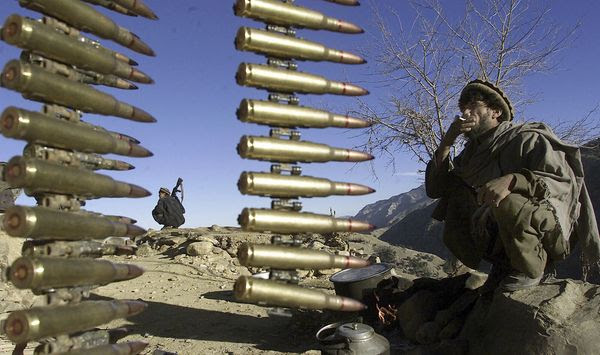 Afghan anti-al-Qaeda fighters rest at a former al Qaeda base in the White Mountains near Tora Bora on Wednesday, Dec. 19, 2001, behind a string of ammunition found after the retreat of al-Qaida members from the area. (AP Photo/David Guttenfelder) ** FILE **